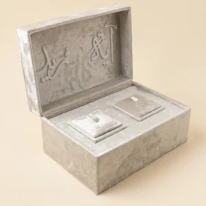 Ring box open at an angle showing raised calligraphy lid lettering and velvet interior cushions