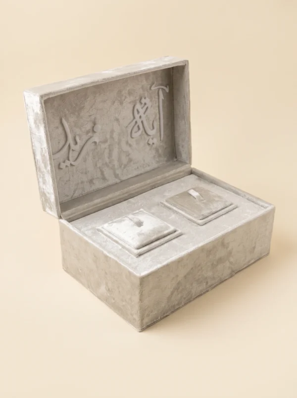 Ring box open at an angle showing raised calligraphy lid lettering and velvet interior cushions