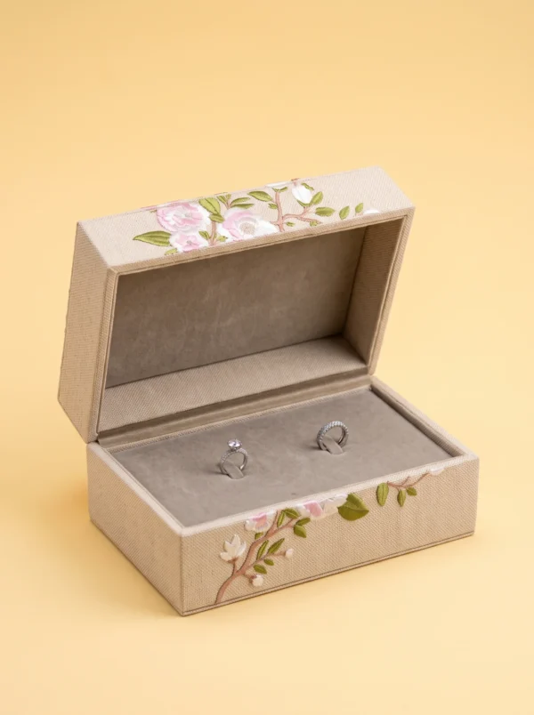 Ring boxes: linen-weave box with embroidered pink roses, open to show two rings on taupe lining