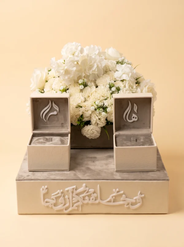 علبة مفصّلة من الجلد الكريمي، منظر أمامي مع خط عربي وعلبتي خواتم وزهور بيضاء
